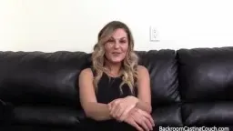 Blonde MILF mit großen Brüsten auf schwarzer Ledercouch