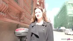 Junge Frau in Lederjacke vor Hausfassade, sonniger Tag