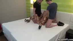 Blonde mit schwarzer Netz-Bodysuit auf weißem Bett