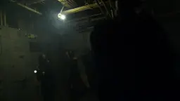 Blonde Polizistin mit taktischer Weste kniet in dunklem Van.