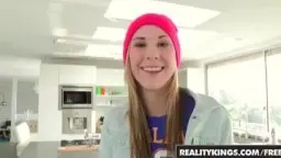 Blonde junge Frau in pinker Mütze lacht in heller Küche