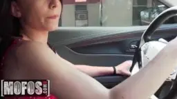 junge Frau mit brünetten Haaren fährt Auto, kurzes rotes Kleid