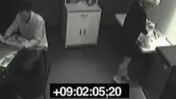 Frau kniet vor sitzendem Mann in kleine Küche