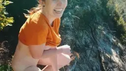 Frau in orangem Shirt hockt auf Klippe, pinkelt am Meer.