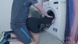 Stiefmutter in rosa Tanga, Hand auf Po vor Waschmaschine